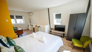 A hotel room with a bed, a desk, a TV, and a wardrobe.