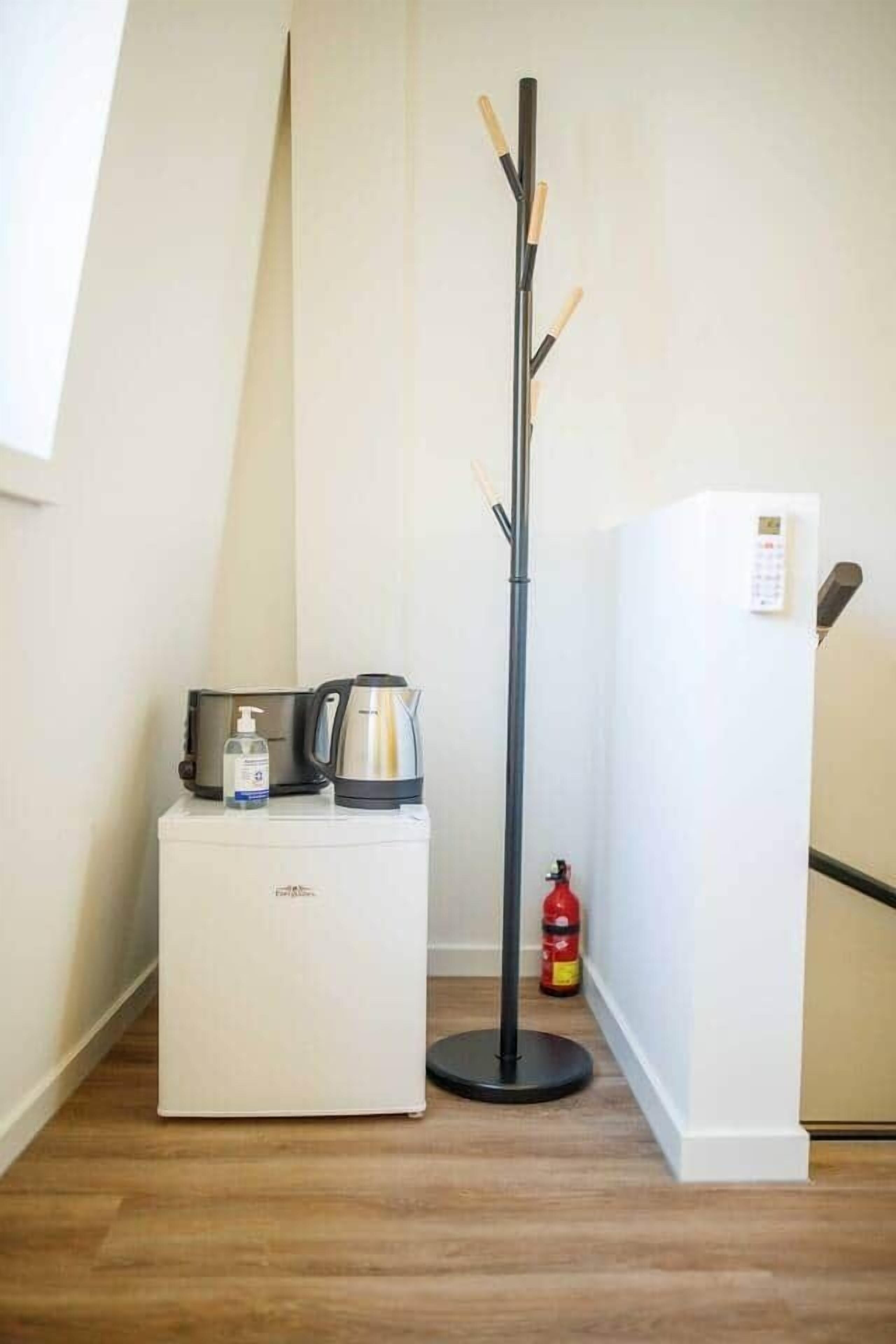 Une petite cuisine équipée d’une machine à café, d’une bouilloire et d’un petit réfrigérateur. Un extincteur est fixé au mur.