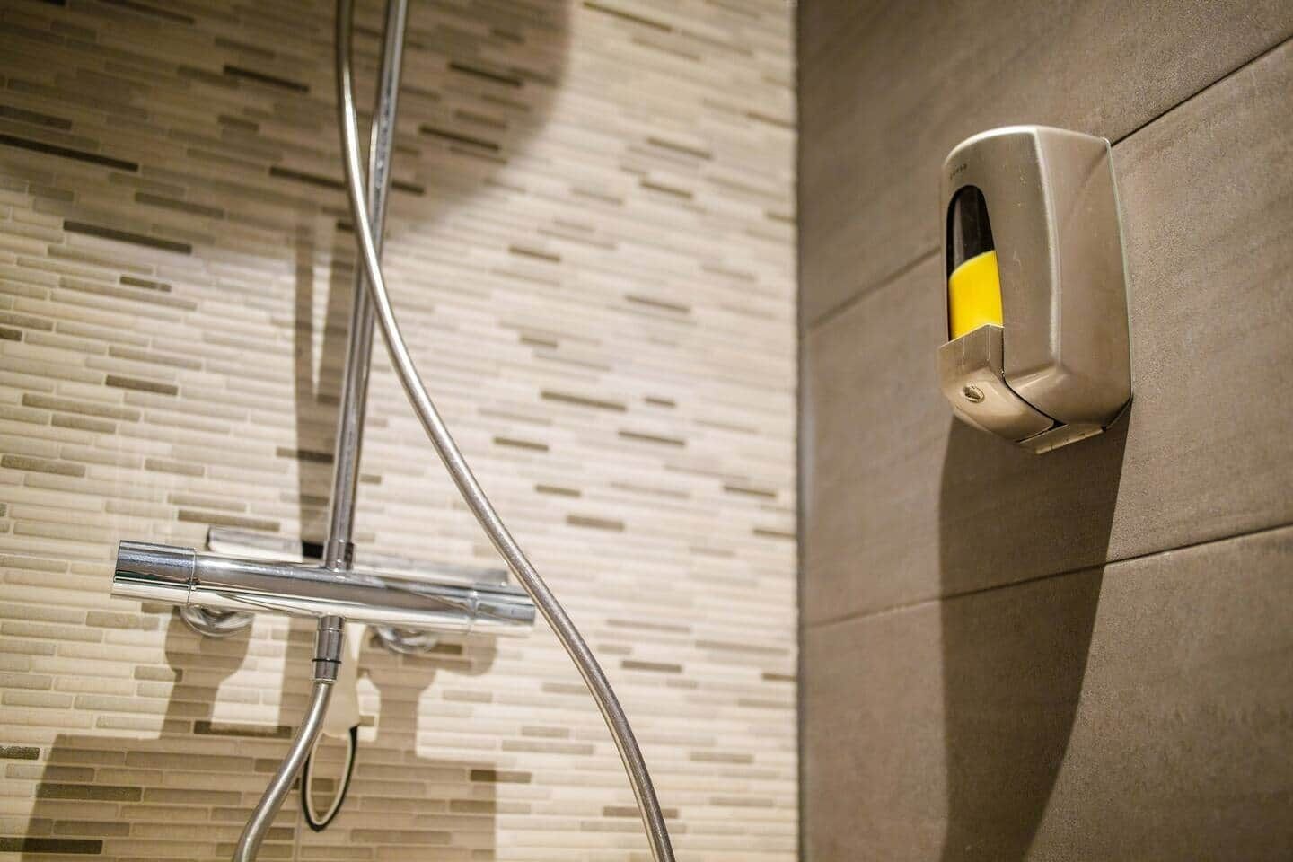 A shower area with a tiled wall and a handheld showerhead.