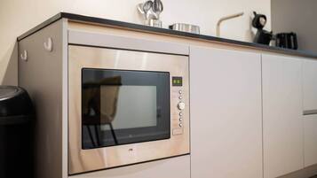 A kitchen with a built-in microwave, a trash bin, and a coffee maker on the countertop.