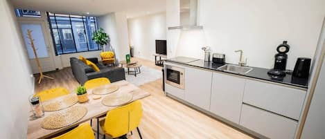 A modern kitchen with a dining area, a sofa, and a coffee machine.
