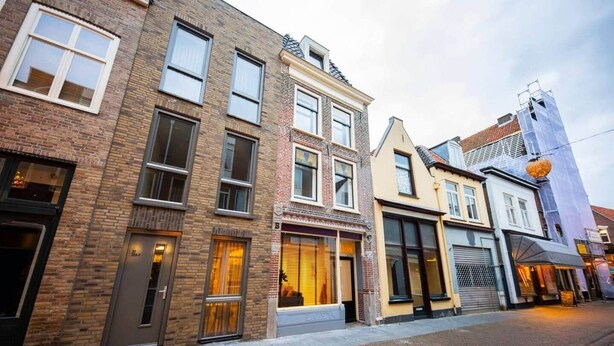 A row of multi-story buildings with brick facades, large windows, and a cobblestone street. - Friendly 50m² Apartment with Terrace (WE-39-A) (Tiel)