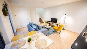A modern living room with a sofa, TV, and dining area with a table and chairs. - Friendly 50m² Apartment with Terrace (WE-39-A) (Tiel)