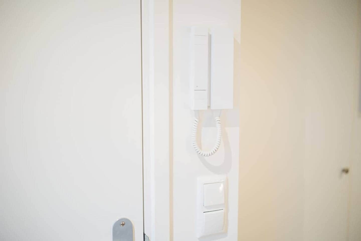 A white door with a telephone mounted on the wall.