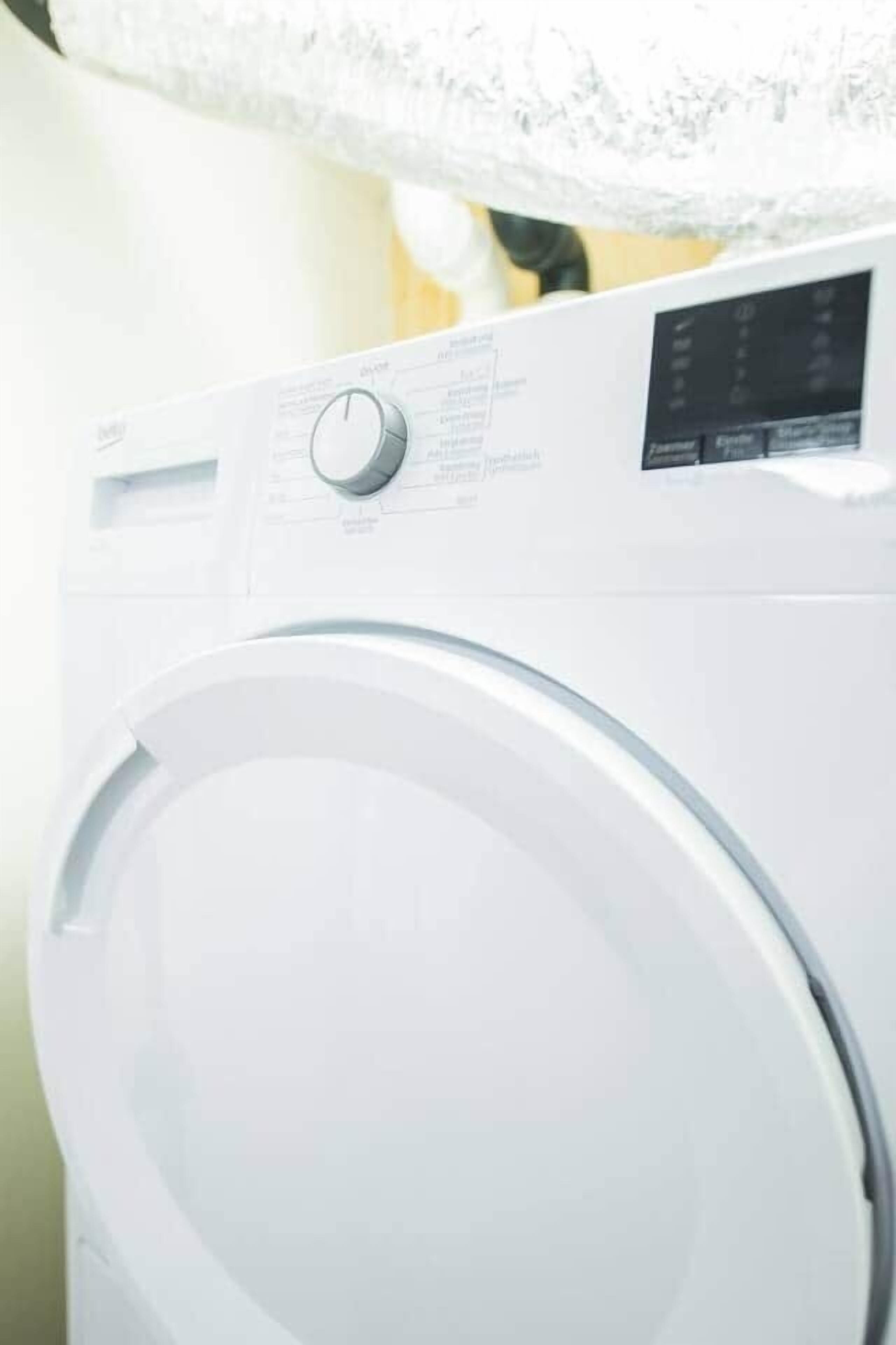 A front view of a white washing machine with a control panel and a digital display.