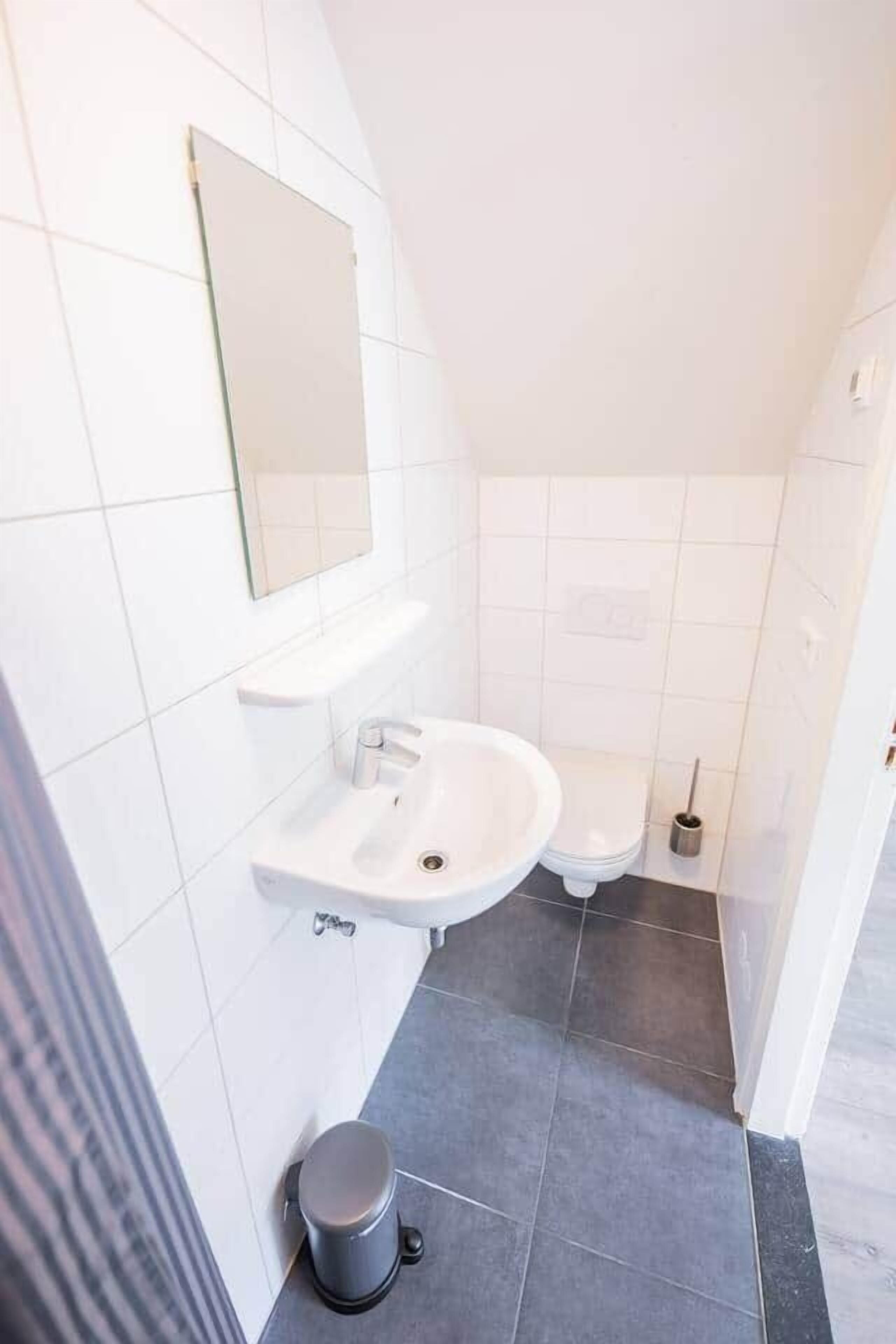 Une salle de bain moderne avec un lavabo blanc, un miroir et des toilettes.