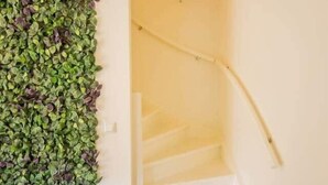 Una escalera con barandilla blanca y pared cubierta de follaje verde y morado.