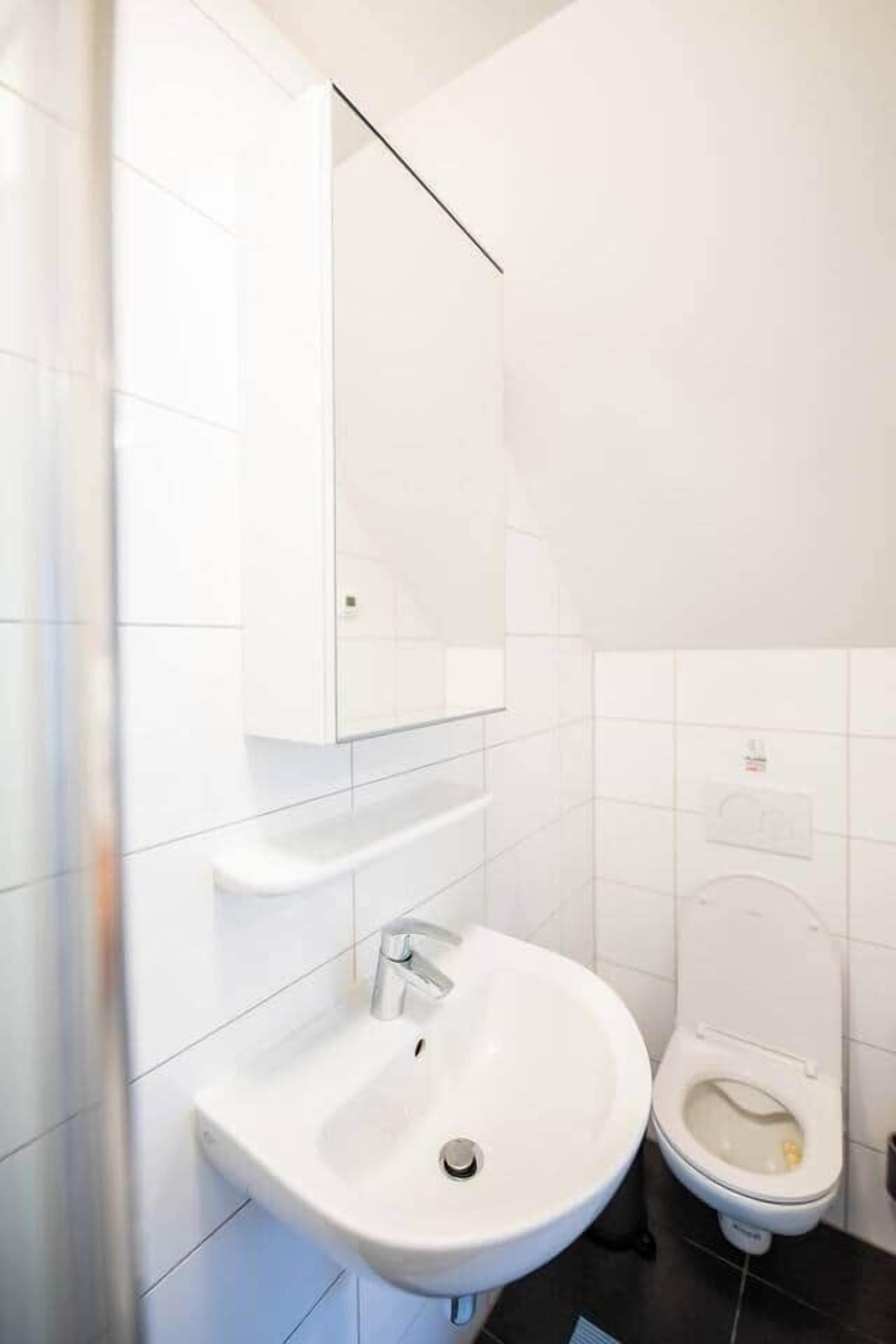 A bathroom with a white sink, a mirror, and a toilet.