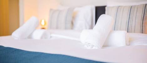 Un lit bien fait, avec du linge de lit blanc et une couvre-lit bleue, des oreillers et une lampe de chevet.