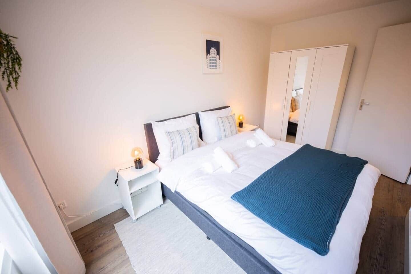 Une chambre bien rangée, avec un lit, des tables de chevet, une commode et une armoire.