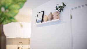 Une étagère blanche ornée de vases décoratifs et d’un tableau encadré accroché au mur.