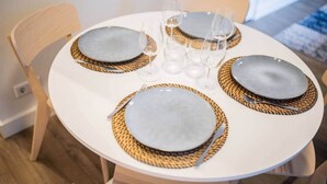 Une table de salle à manger ronde, avec quatre assiettes, chacune accompagnée d’un set de table en fibres tressées.