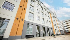 Un edificio residencial de varios pisos con diseño moderno, que presenta una combinación de paredes blancas y anaranjadas, ventanas amplias y un techo plano.