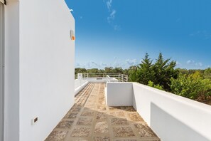 Enjoy panoramic views from this rooftop terrace with a stone floor and white railing.