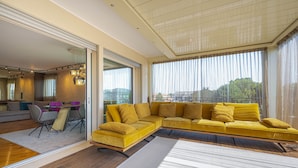 A modern living room with a yellow sectional sofa, a dining table with chairs, and a large mirror reflecting the space. - Venice New Luxury Penthouse with parking (Mestre)