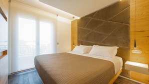 A modern hotel room with a large bed, wooden headboard, and a view of the city through the window. - Venice New Luxury Penthouse with parking (Mestre)