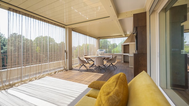 A modern outdoor dining area with a table and chairs, a grill, and a view of greenery through sheer curtains. - Venice New Luxury Penthouse with parking (Mestre)