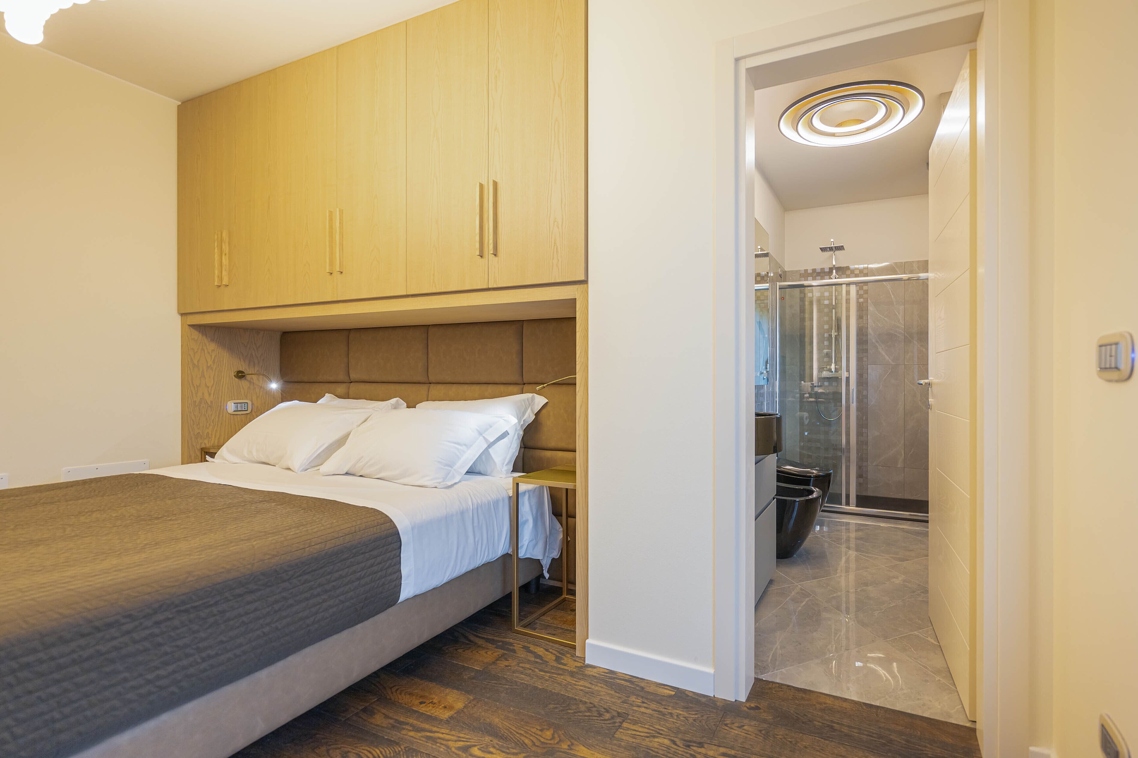 Un dormitorio con cama, armario de madera y baño con ducha.