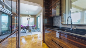 A modern kitchen with a large island, a dining area with a table and chairs, and a view through a glass door. - Venice New Luxury Penthouse with parking (Mestre)