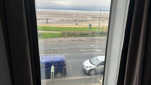 A view through a window of a parking area with a road leading to a beach. - The Clifton Hotel (Morecambe)