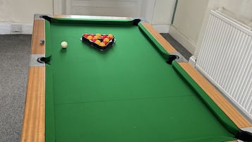 A pool table with balls, a window with a stained glass design, and a radiator.