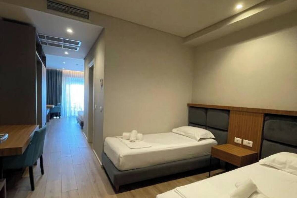 A hotel room with two beds, a desk, and a chair.