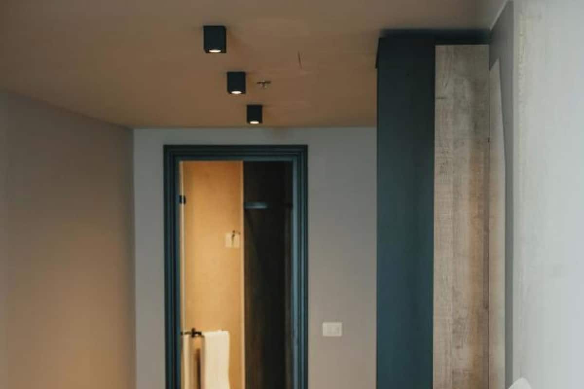 A hotel room with a bed, a door leading to a bathroom, and a small window.
