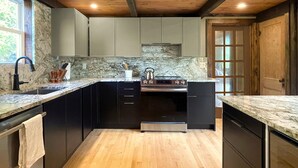 A kitchen with dark cabinets, a marble countertop, and a wooden ceiling. - Spectacular Views, Private River Access Home (Wilmington)
