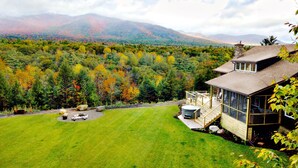 A house with a large yard, a hot tub, and a deck overlooking a forested area with mountains in the background. - Spectacular Views, Private River Access Home (Wilmington)