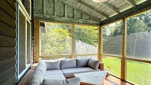 A covered outdoor seating area with a wooden ceiling and large windows. - Spectacular Views, Private River Access Home (Wilmington)