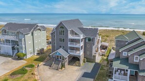 Una propiedad frente a la playa con varias construcciones, incluyendo una casa de dos pisos destacada con un balcón y un edificio más pequeño identificado como "Dream Catcher".