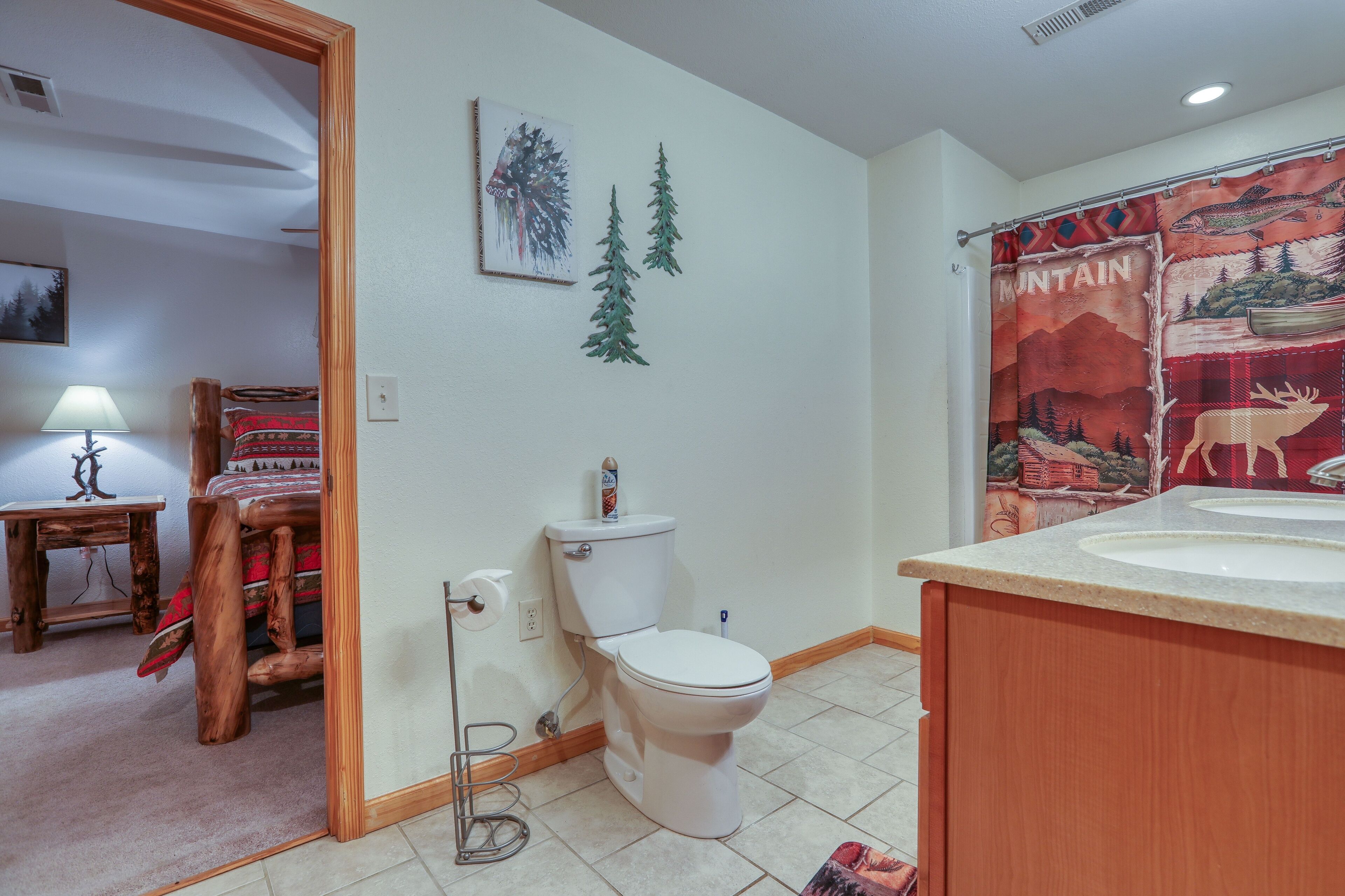 Een badkamer met toilet, wastafel en een douchegordijn met een berglandschap.