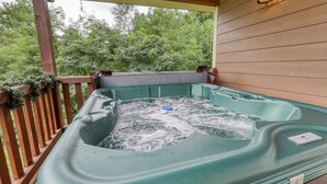 A hot tub on a wooden deck with a view of trees.