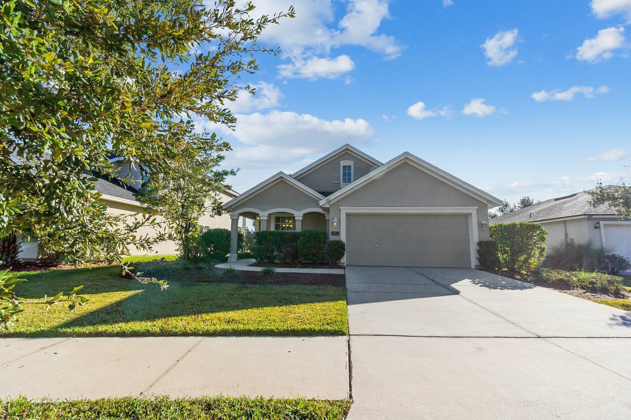 A two-story house with a garage, a front lawn, and a tree.