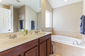 A bathroom with a double sink, a large mirror, a bathtub, and a window. - Exquisite Waterfront Retreat - Pet Friendly by RedAwning (St. Augustine)