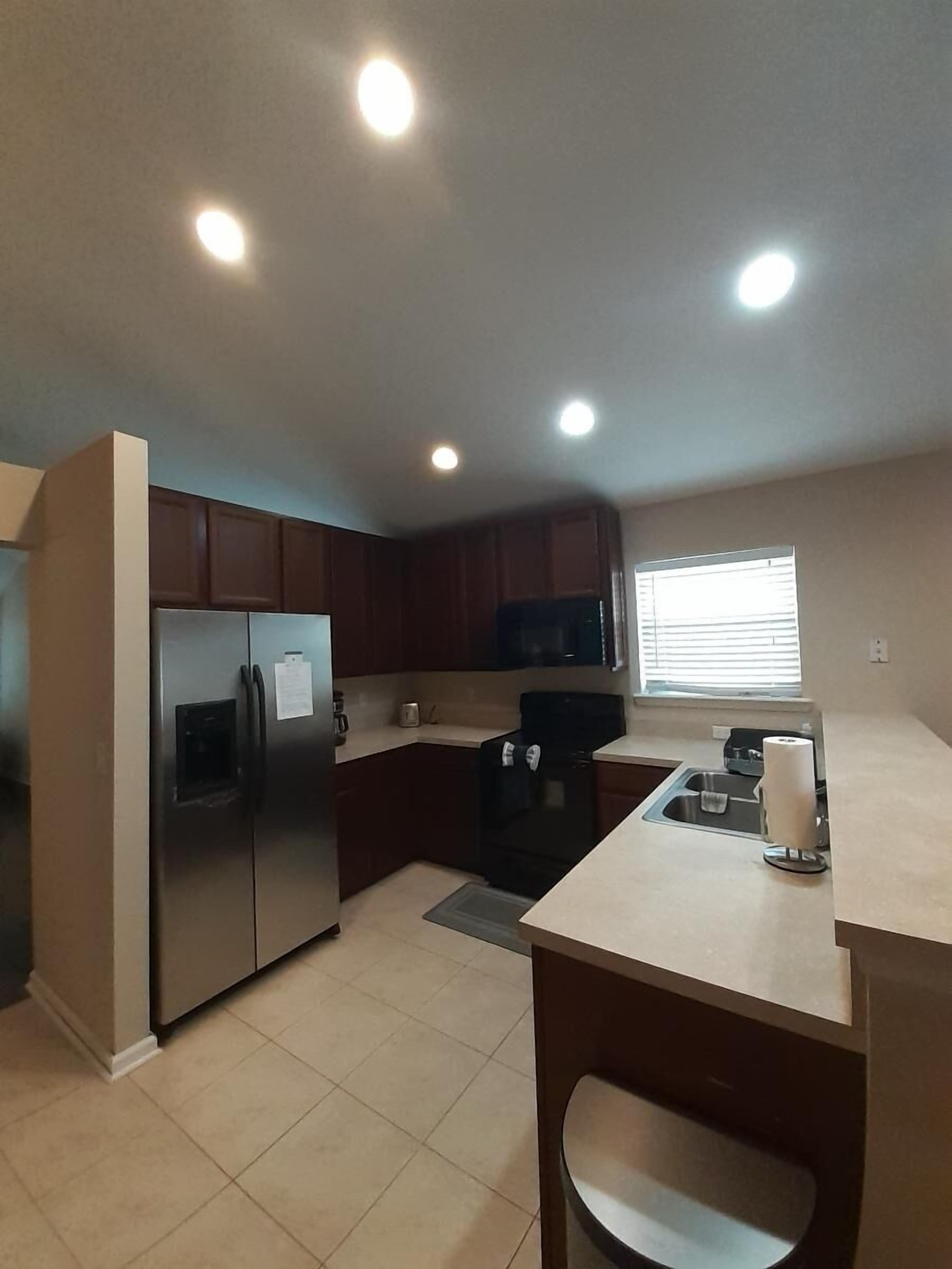 A compact kitchen with a refrigerator, stove, microwave, and a small sink.