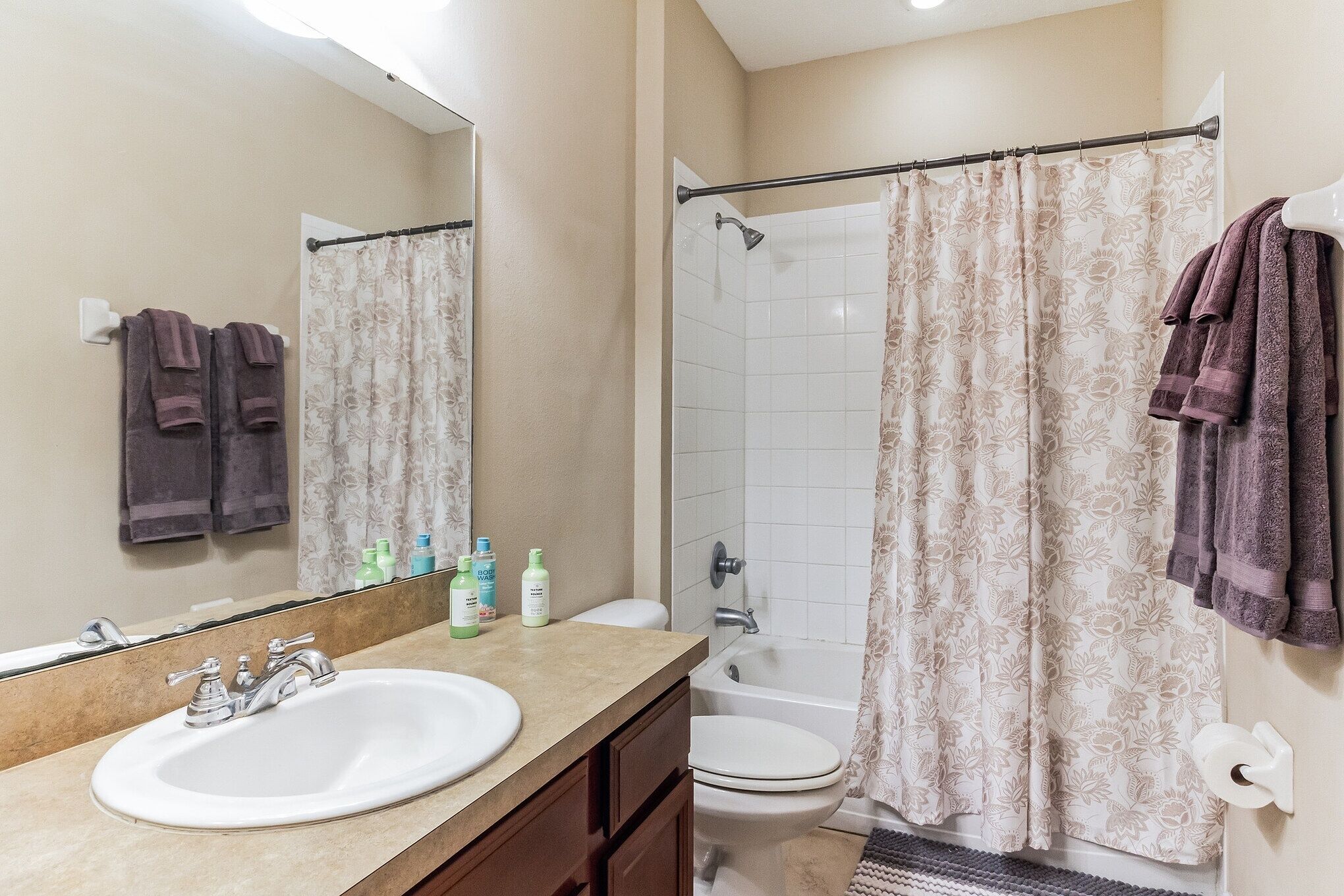 A bathroom with a sink, mirror, shower, and toilet.