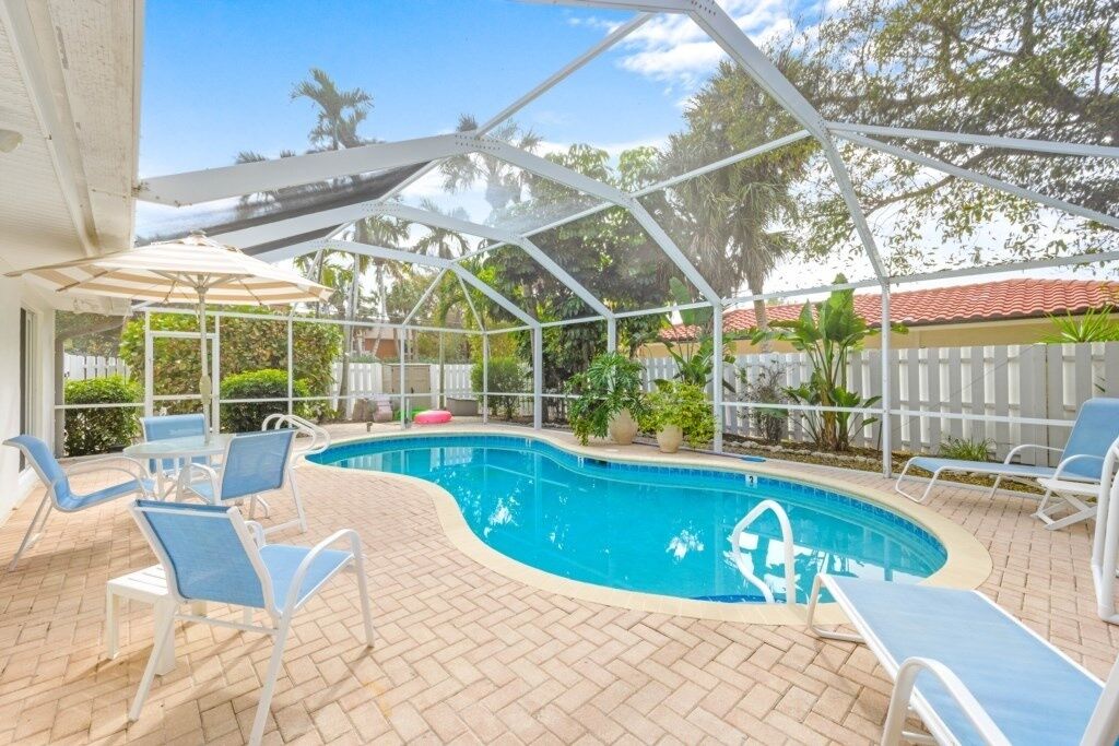 A covered outdoor swimming pool with lounge chairs and umbrellas.