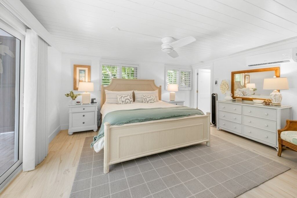 A bedroom with a bed, nightstands, a dresser, and a ceiling fan.