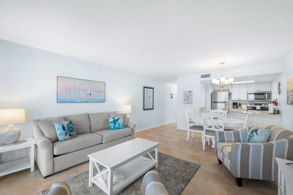 A modern living room with a sofa, a coffee table, and a dining area with a table and chairs.