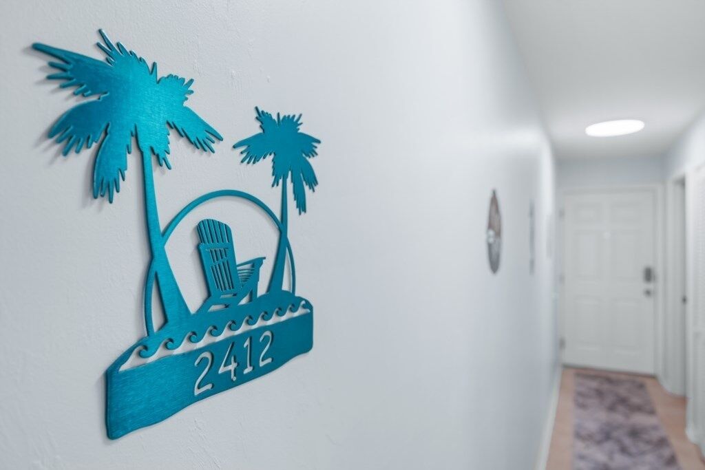 A hallway with a wall-mounted sign featuring palm trees and a beach scene, indicating a tropical theme.
