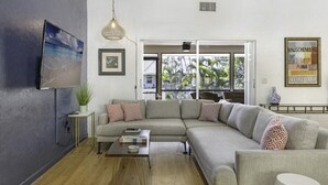 Een moderne woonkamer met een modulaire bank, een salontafel en een aan de muur bevestigde televisie.