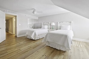Ein Schlafzimmer mit zwei Betten, einem Deckenventilator und Holzboden.