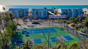 A beachfront hotel with multiple buildings, a tennis court, and palm trees. - South Seas Beach Villa 2535 4 Bedroom Home by RedAwning (Captiva)
