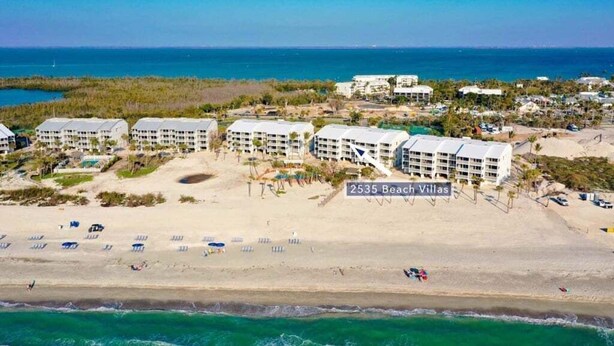 A beachfront hotel named 2535 Beach Villas with multiple buildings, a sandy beach, and the ocean in the background. - South Seas Beach Villa 2535 4 Bedroom Home by RedAwning (Captiva)