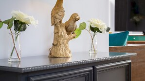 A dark wooden cabinet with a green lamp on top, two vases with white flowers, and a decorative owl figurine.