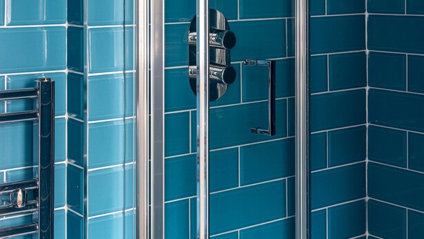 A bathroom with blue-tiled walls and a glass shower enclosure. - One Bedroom Apartment in Marylebone (London)