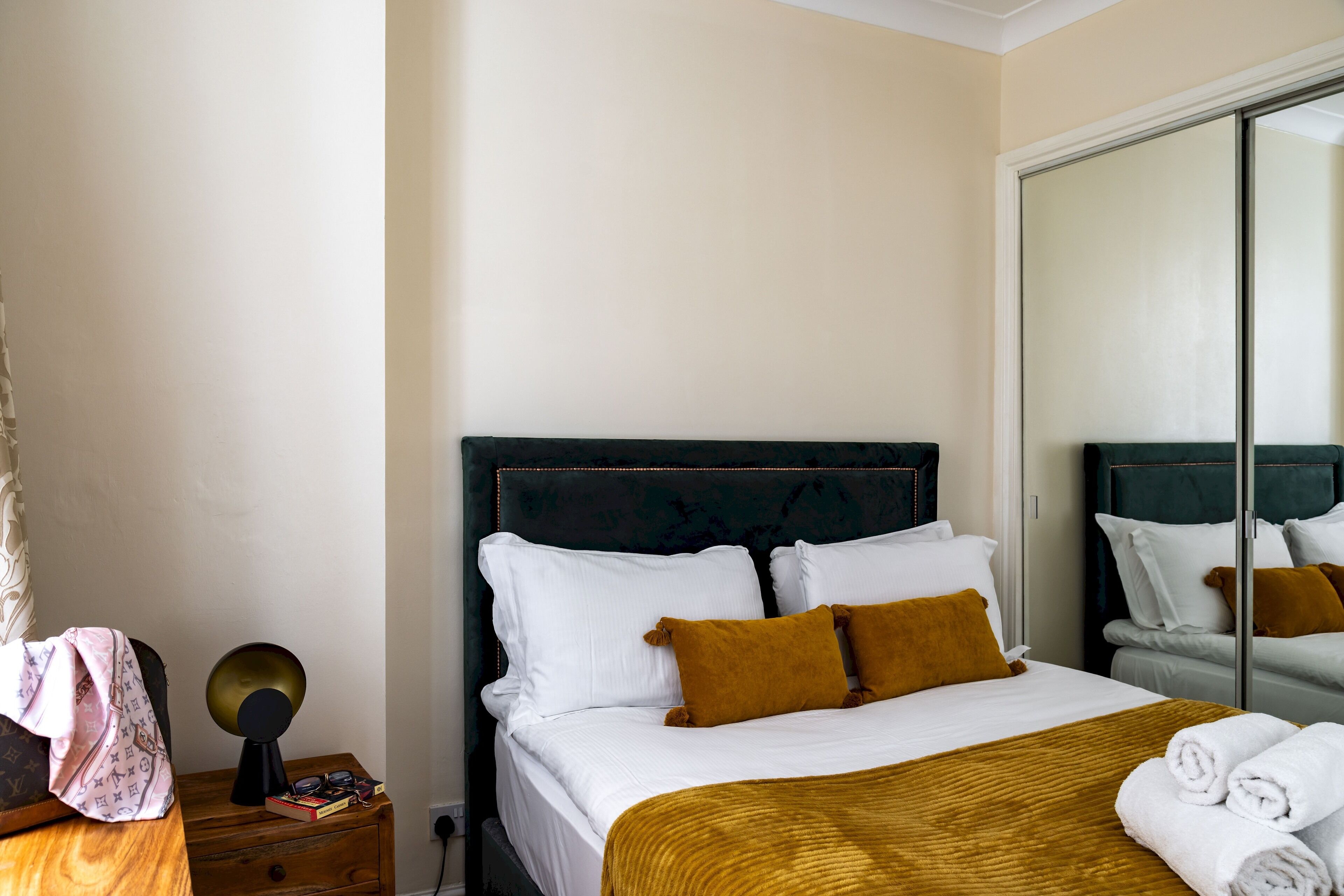 Una habitación de hotel con cama, mesita de noche, espejo y armario.