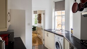 A kitchen with a washing machine, a sink, and hanging pots. - One Bedroom Apartment in Marylebone (London)