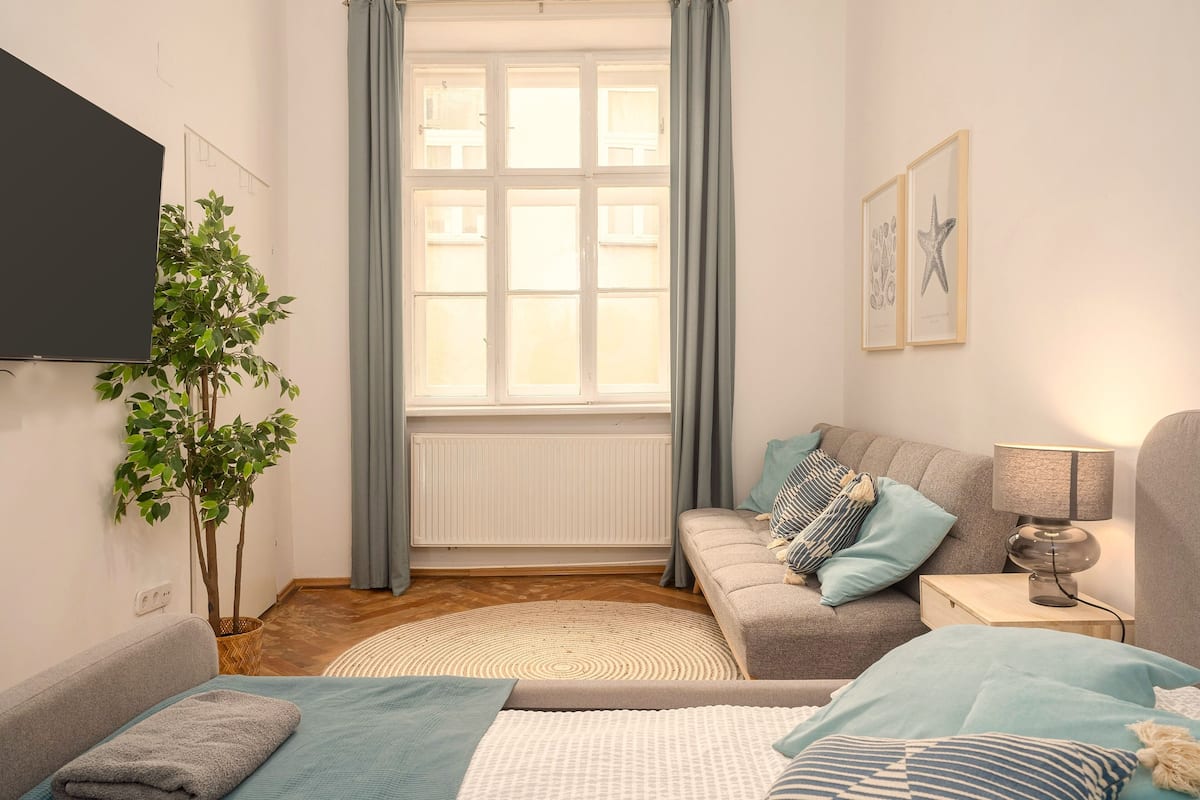 A modern living room with a sofa, a coffee table, a TV, and a window with curtains.